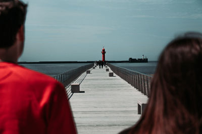 Rear view of people on pier over sea against sky