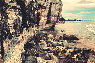 Rock formation on beach against sky