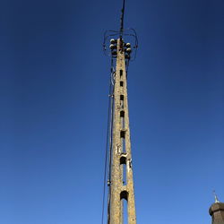 Low angle view of crane against clear blue sky