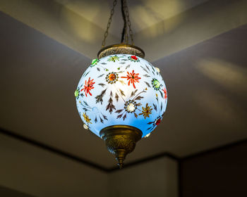 Low angle view of illuminated pendant light hanging on wall