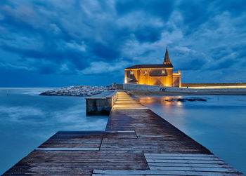 View of building by sea against cloudy sky