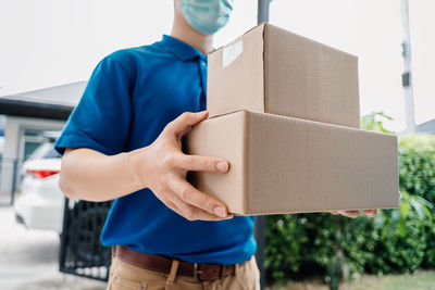 Midsection of man holding mobile phone in box