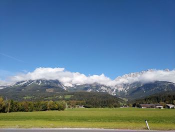 Scenic view of field and mountains against blue sky