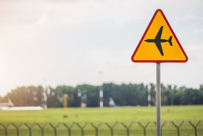 Close-up of road sign on field against sky