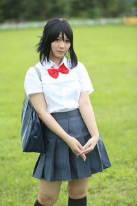 Portrait of young woman in school uniform standing in park