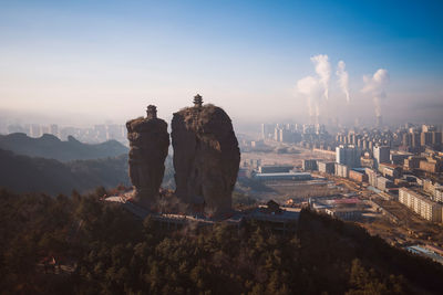 Statue in city against sky