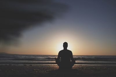 Young man in meditation near the sea. concept of pray. adult practice yoga on the beach at sunset.