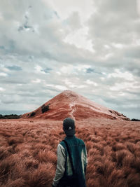 Rear view of man standing on land against sky