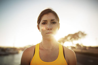 Portrait of confident female athlete against clear sky during sunset