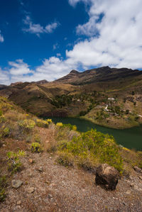 Scenic view of land by lake against sky