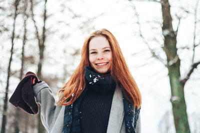 Portrait of smiling young woman at forest in winter