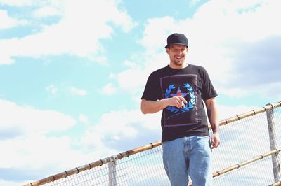 Portrait of mid adult man in casuals with cigarette against sky