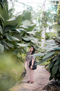 Portrait of young woman standing by plants