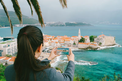 Woman photographing at sea shore