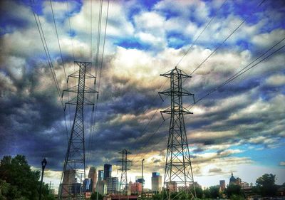 Low angle view of electricity pylon against cloudy sky