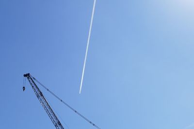Low angle view of cranes against clear blue sky