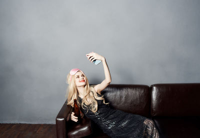 Young woman sitting on sofa against wall