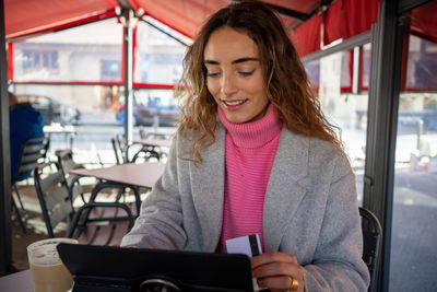 Portrait of young woman using mobile phone in cafe