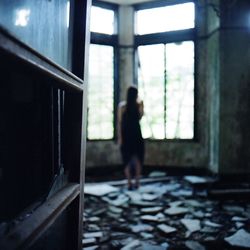 Rear view of woman looking through window