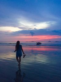 Rear view of woman at beach during sunset