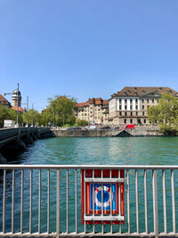 View of canal by buildings against clear blue sky