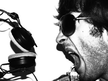 Close-up of young man screaming by headphones on sunny day