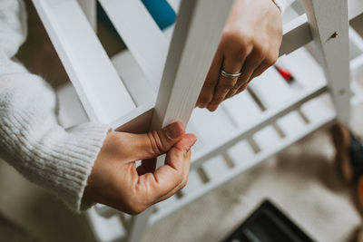 Cropped hands of woman making wooden chair at home