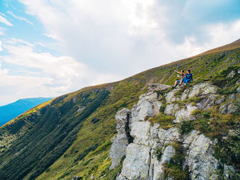 Rear view of man hiking on mountain against sky