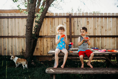 Two young kids sitting on picnic table eating watermelon in spring