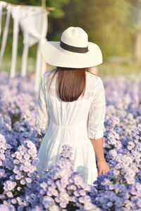 Rear view of woman standing by purple flowering plants