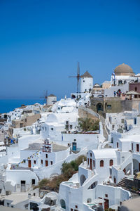High angle view of townscape by sea against clear blue sky