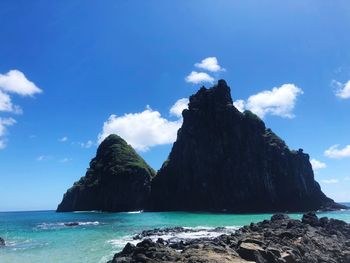 Scenic view of rocks by sea against blue sky