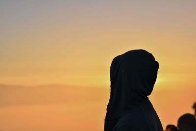 Woman wearing headscarf against sky during sunset