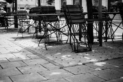 Empty chairs and tables at sidewalk cafe against buildings