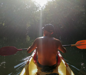 Rear view of man and woman on boat against trees