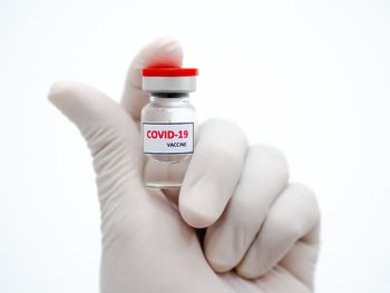 Close-up of hand holding bottle against white background