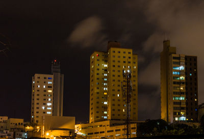 Illuminated buildings in city against sky at night