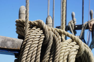 Low angle view of rope tied on metal against sky