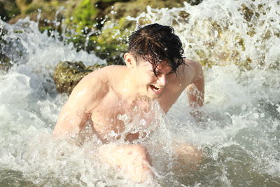 Close-up of shirtless man splashing water in lake