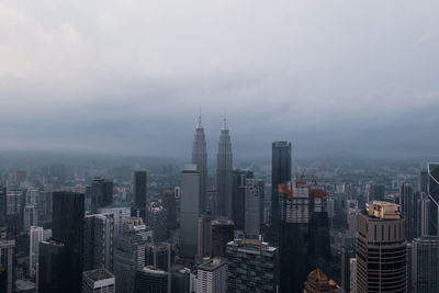 Buildings in city against cloudy sky