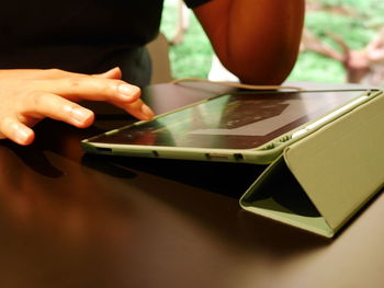 Midsection of man using mobile phone on table