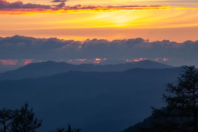Scenic view of silhouette mountains against orange sky