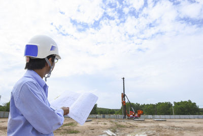 Side view of man holding construction site against sky