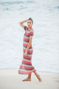 Full length portrait of young woman standing at beach