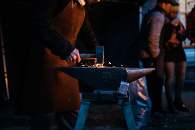 Midsection of blacksmith working at night