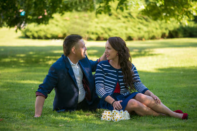 Man and woman sitting on grassy field at park