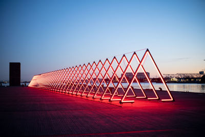 Metallic structure against buildings in city against clear blue sky