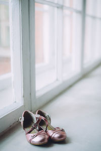 Close-up of sandals on floor by window