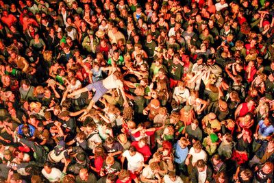 Men being carried by group of people during concert