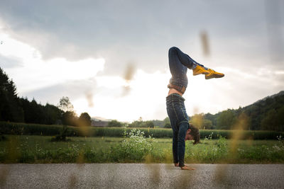 Side view of man standing on field against sky